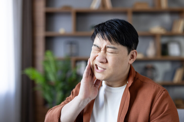 Asian man suffering from severe dental pain indoors